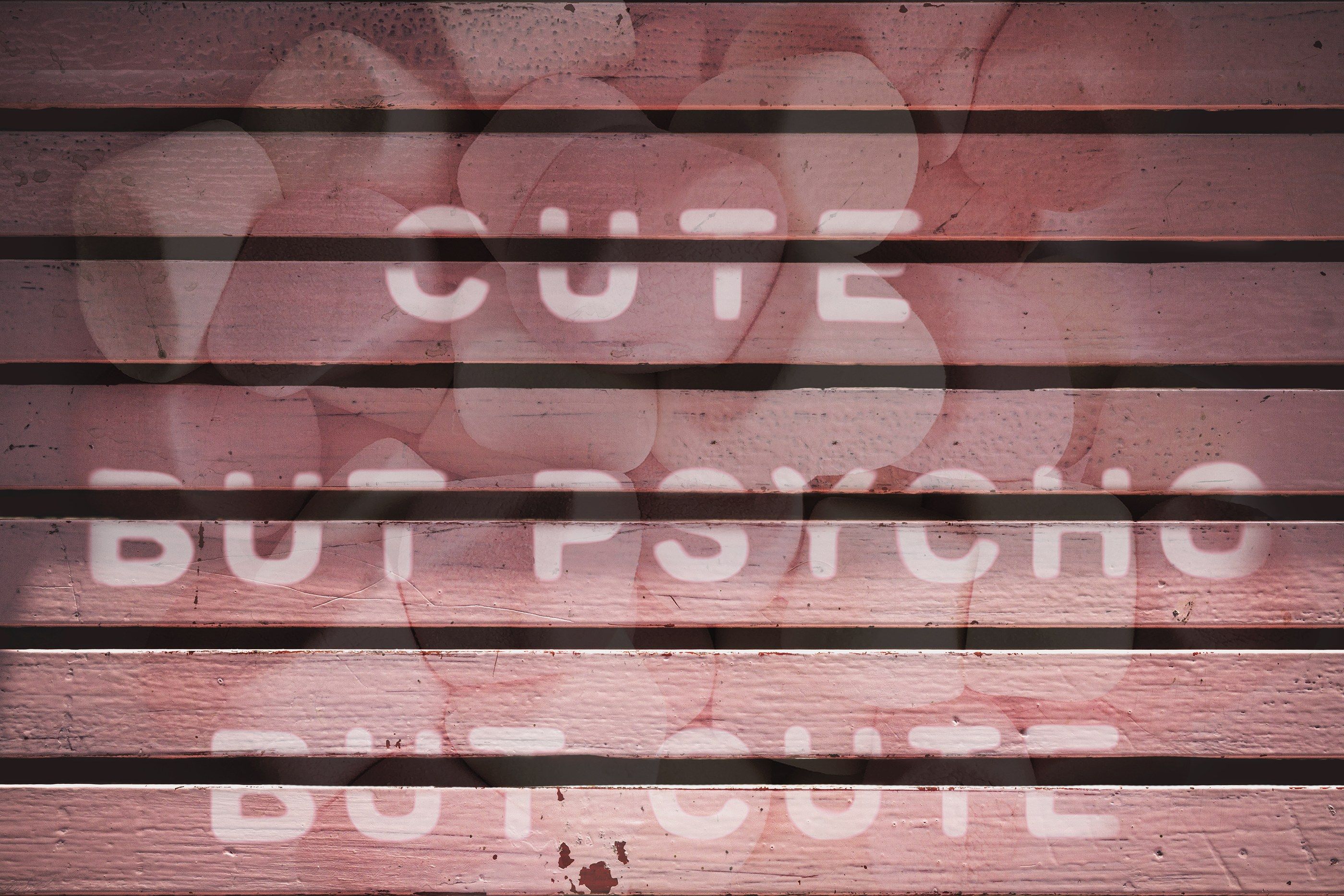 Tablones de madera rosa con la frase "Cute but psycho but cute" en letras blancas y siluetas de corazones